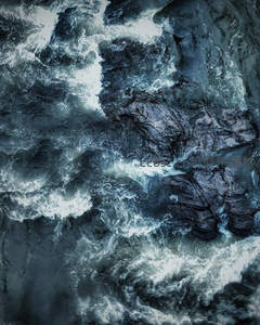 航拍视角下的激流漩涡，水流与岩石交织成抽象画卷