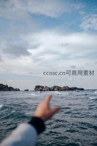 伸手指向远方海岛的视角