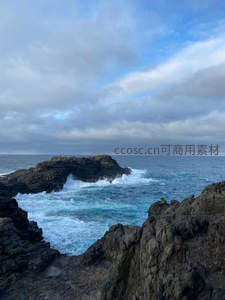 海浪冲击礁石拱门，云层密布天空苍茫