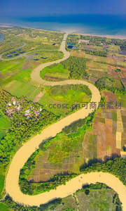 热带河湾航拍，泥黄河水环绕翠绿稻田与村落