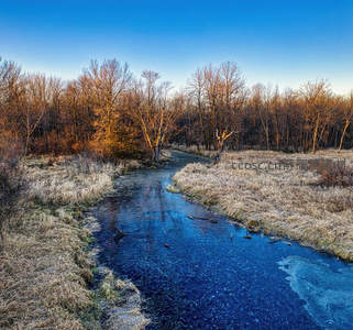 冰封溪流映冬阳，枯草环抱静谧河