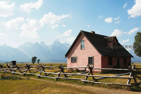 粉红农舍前木栅栏与雪山背景的西部风情