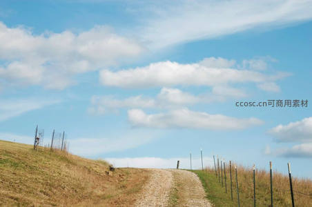 乡野小径通向蓝天白云下的山坡