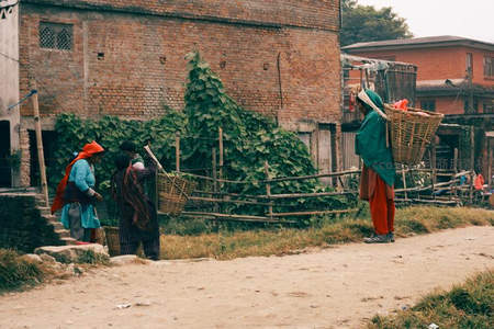 乡村妇女背竹筐行走在砖墙小径
