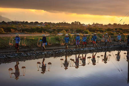 夕阳下渔夫列队踏水归家