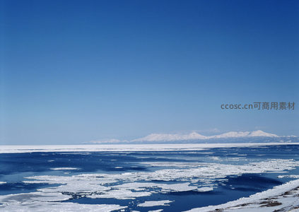 远山雪峰下的冰封湖面全景
