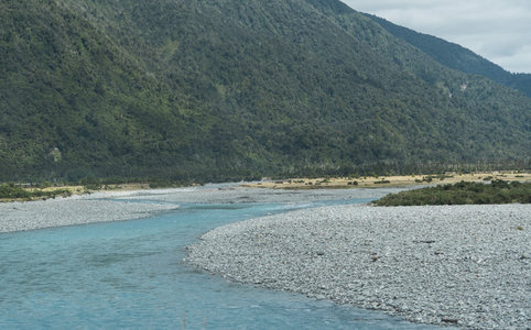 青翠山麓下，蜿蜒河流穿石滩