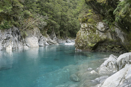 碧蓝河湾被苍翠山林与苔藓巨石温柔环抱