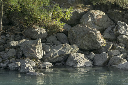 河岸巨石堆叠，绿树掩映