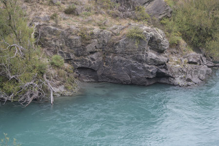 湍流绕过暗礁，岩洞隐现水边绿