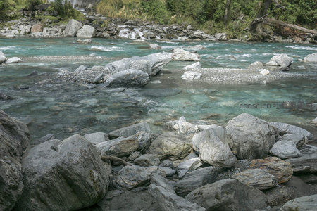 前景岩石堆叠映衬清澈湍急河流