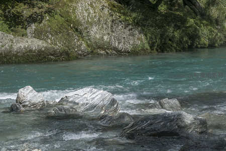 碧蓝河水绕石而行，波光粼粼如镜面