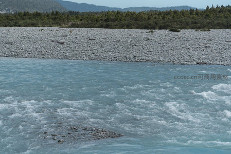 湍急蓝河穿石滩，远山绿林映水间