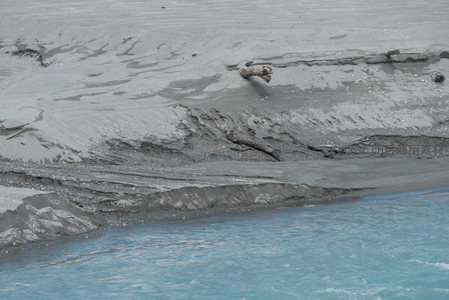 冰川融水冲刷河岸，灰泥与蓝水交织