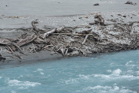 河滩堆积枯枝败木，流水轻抚石砾