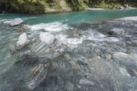 激流拍打岩层溅起白色水花如丝带飘舞