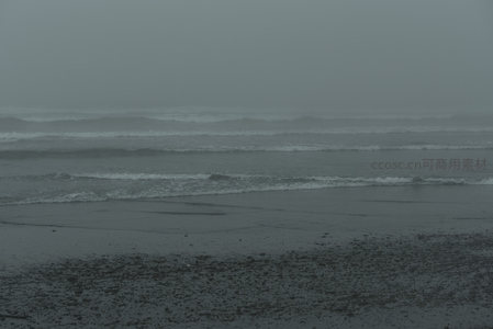 雾霭中的海岸线，浪花轻拍湿润沙滩