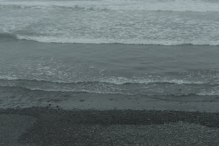 海浪层层推进，泡沫轻吻黑砂海岸线