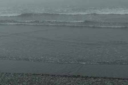 远眺海面波涛起伏，近处卵石滩静默如画