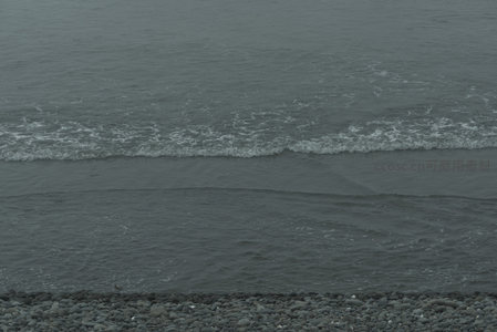 灰暗海浪轻拍卵石滩的静谧瞬间