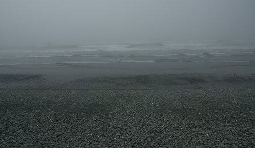 灰雾弥漫的海滩，细浪无声涌向岸边