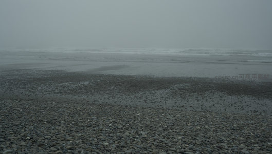 雾霭沉沉的海边，潮水退去留下斑驳印记