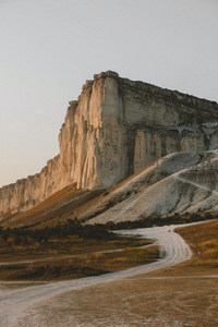夕阳映照白色悬崖，土路蜿蜒其间