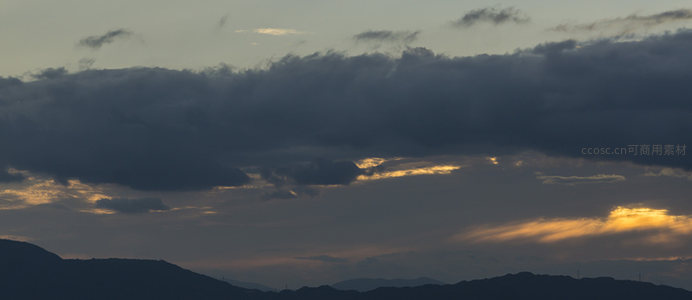 山脊之上云层翻涌，金色霞光穿透缝隙照亮大地