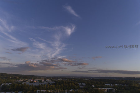 蓝天下飘逸云丝与城市绿意交织