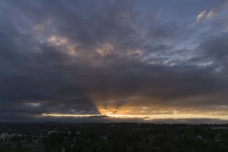 云层缝隙透出金色光芒的城市黄昏