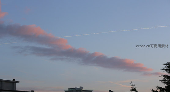城市上空粉云飘逸，航迹划破暮色长空