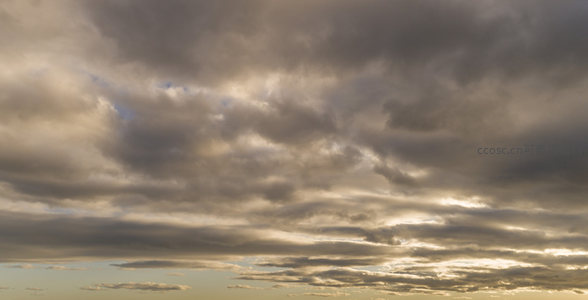 夕阳穿透灰云洒下温暖光束