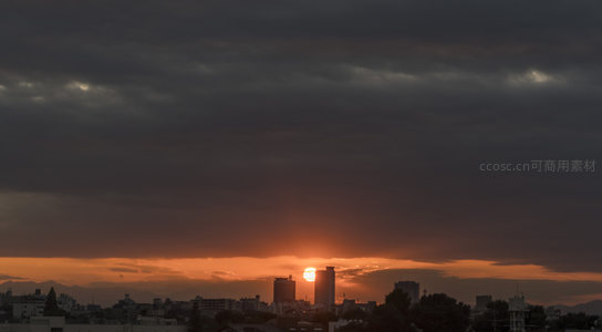 城市上空的黄昏，夕阳穿透厚重云层