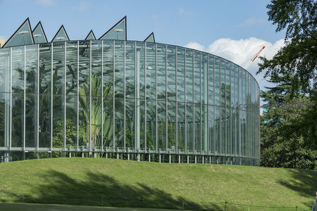 弧形玻璃温室映衬蓝天白云下的静谧绿坡