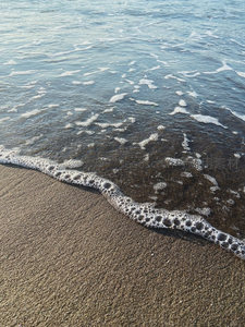 海浪轻吻沙滩，泡沫如雪般消散