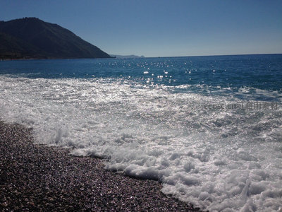 阳光洒在海岸，浪花轻吻鹅卵石滩