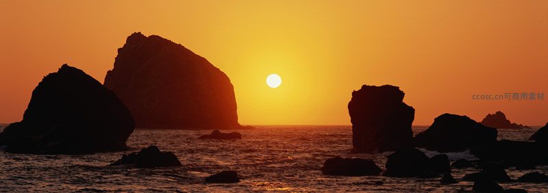 夕阳西下，海面波光粼粼，巨石剪影如画