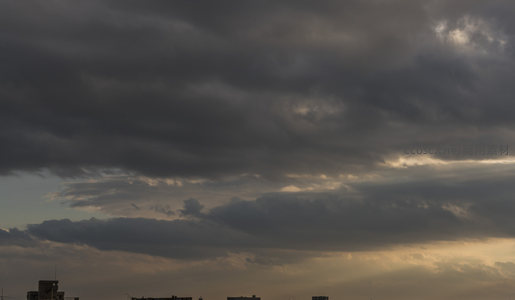 暮色中城市剪影与撕裂云层的光束