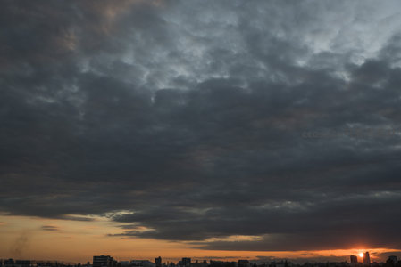 城市上空厚重云层与落日余晖交织