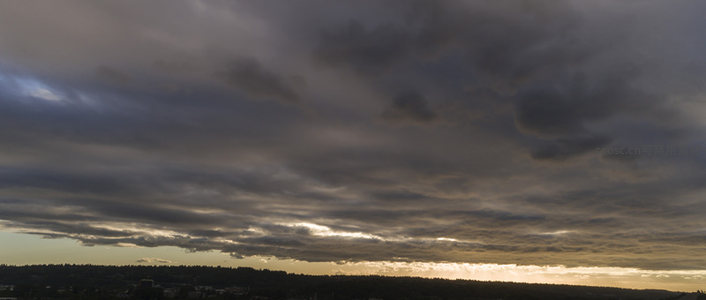 暮云低垂，霞光破云照亮山脊线