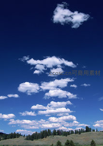 蓝天白云下的青翠山丘与松林