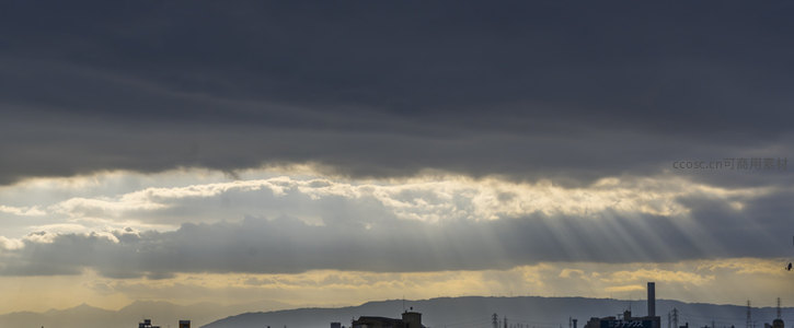 城市上空，阳光穿透云隙洒向大地