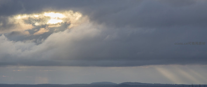 云层缝隙透出金色光芒照亮大地
