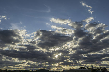 夕阳余晖穿透云层，染亮城市上空