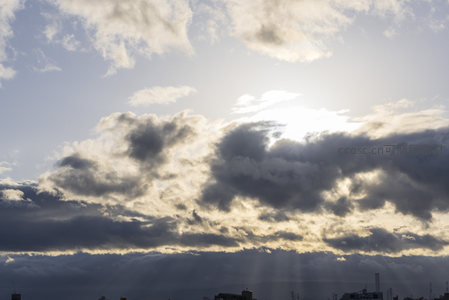 云层缝隙透出金色阳光的城市天际线
