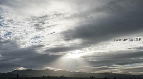 阳光刺破云层，照亮城市山峦