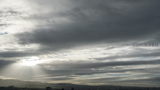云层缝隙透出的光芒照亮城市与远山
