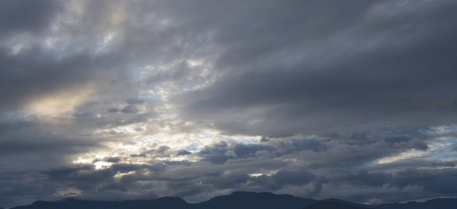 云层缝隙透出金色光芒，山峦静默如画