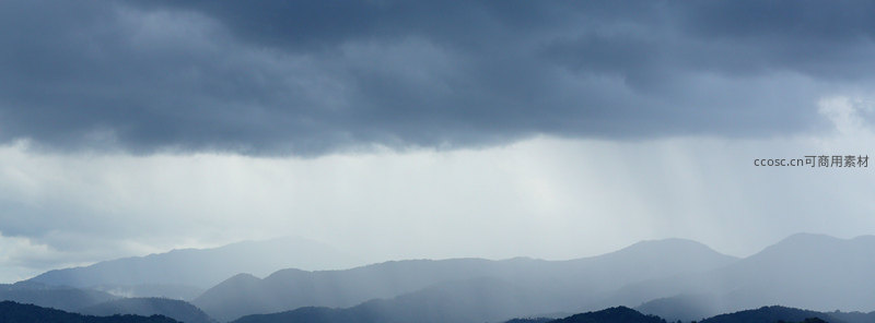 乌云压顶，雨幕倾泻，山峦笼罩在朦胧水汽中。