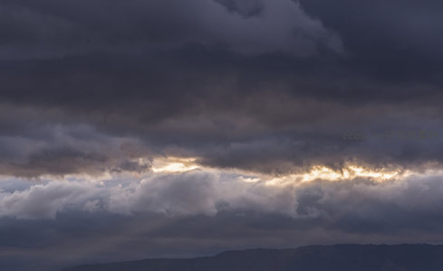 乌云密布天际线，霞光穿透云层缝隙